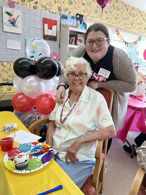 Wesley Manor Assisted Living Community offering assisted living and continuing care retirement community (CCRC) services in Louisville, KY, resident enjoying a birthday celebration with a staff member nearby