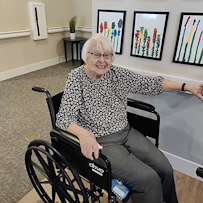 Cascade Creek Memory Care resident in a wheelchair smiling and pointing