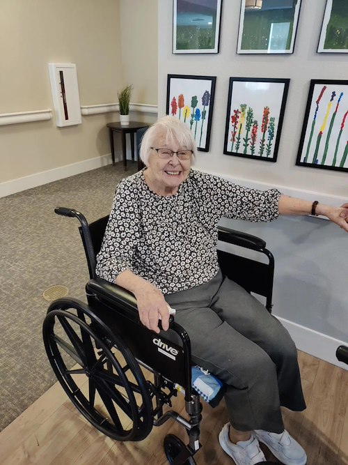Cascade Creek Memory Care resident in a wheelchair smiling and pointing