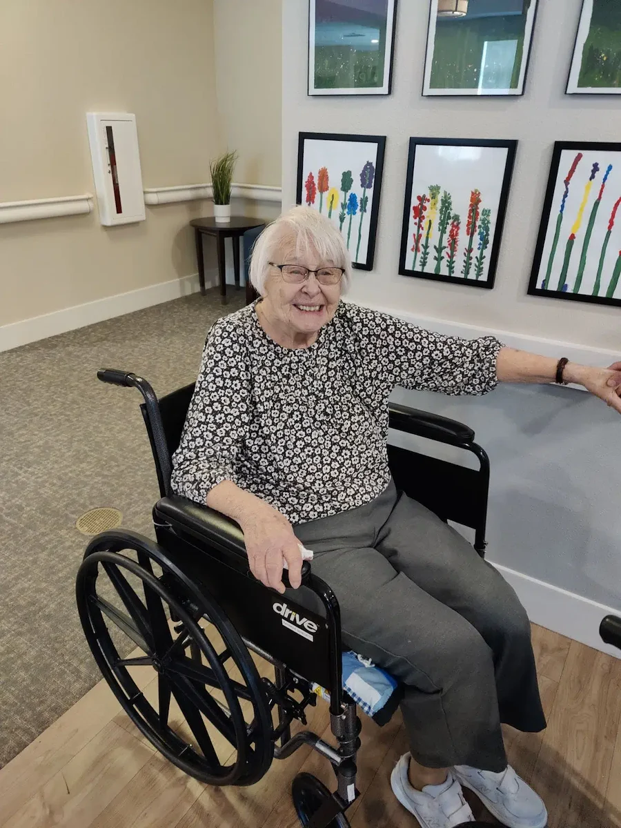 Cascade Creek Memory Care resident in a wheelchair smiling and pointing