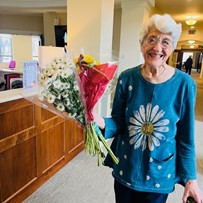 A resident of the Waters of Highland Park enjoying flowers donated by Trader Joes