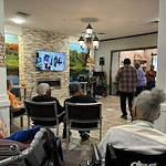 Seniors in assisted living and memory care at Charter Senior Living of Hazel Crest in Hazel Crest, IL, gathered to enjoy live music performed by a musician, with some residents dancing and others listening in a lively community event.