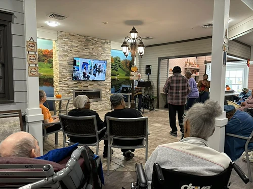 Seniors in assisted living and memory care at Charter Senior Living of Hazel Crest in Hazel Crest, IL, gathered to enjoy live music performed by a musician, with some residents dancing and others listening in a lively community event.