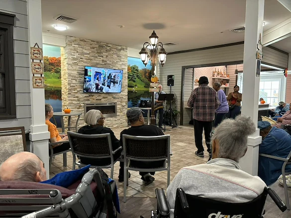 Seniors in assisted living and memory care at Charter Senior Living of Hazel Crest in Hazel Crest, IL, gathered to enjoy live music performed by a musician, with some residents dancing and others listening in a lively community event.